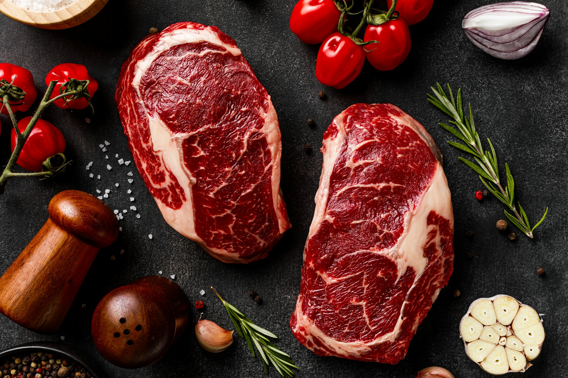 premium raw ribeye steak on dark stone surface, professional food photography, high-end, detailed meat texture